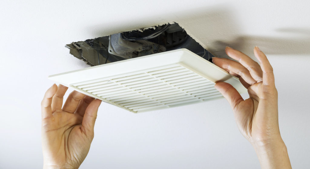 photo of a person's hands removing a bathroom ceiling fan cover