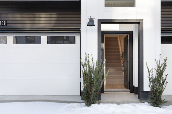 photo of the open front door to a modern townhouse with white siding and dark brown trim